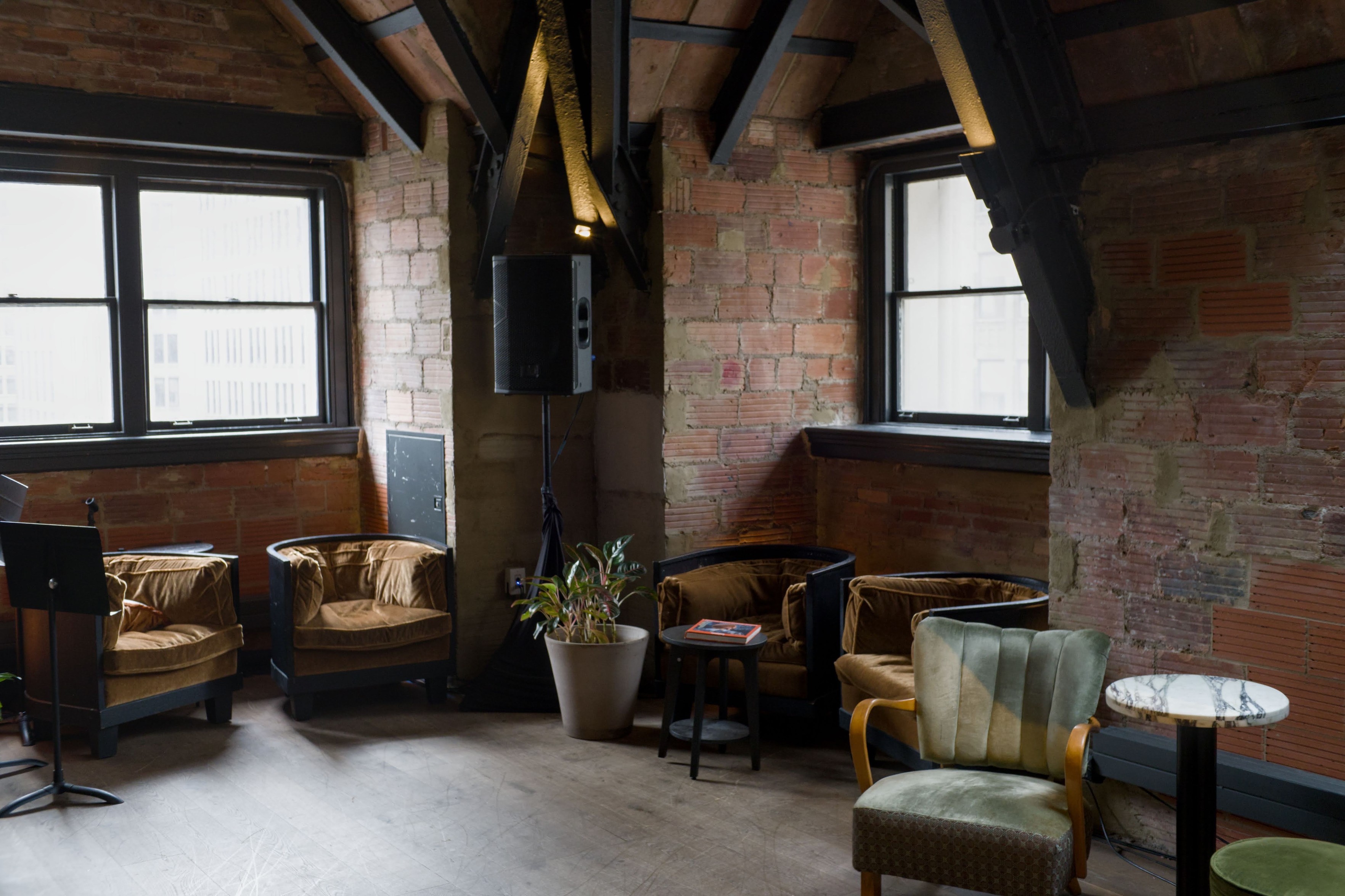 A color photo of the top floor of the Fotografiska museum. Sunlight creeps in through the windows and into the velvet furniture sitting in front of exposed brick. 