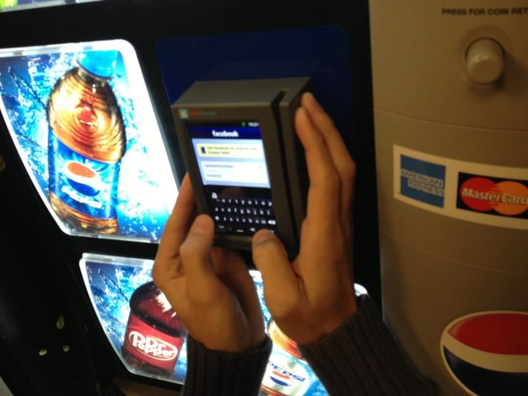 Photo of someone that has hacked the credit card display on a Pepsi vending machine. It's showing the Facebook login screen with an onscreen keyboard.