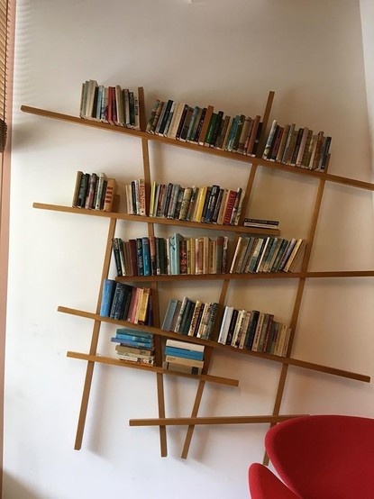 Photo of a hanging bookshelf with books that doesn't have any level shelves on it. The non-aligned vertical wood sections keep the books from sliding. It looks very precarious, but it keeps all the books in place. So what more could you ask for?