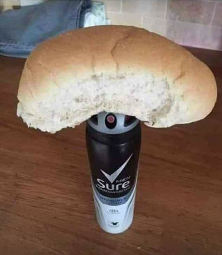 Photo of a bread roll on top of a spray bottle of Sure Men's deodorant.