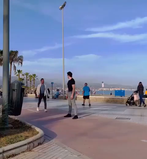 Video of two people near a broadway type of area doing continually summersaults (well, kinda) by grappling each other with their arms while facing the same direction so that their sideway flips always lands on one or other's feet.