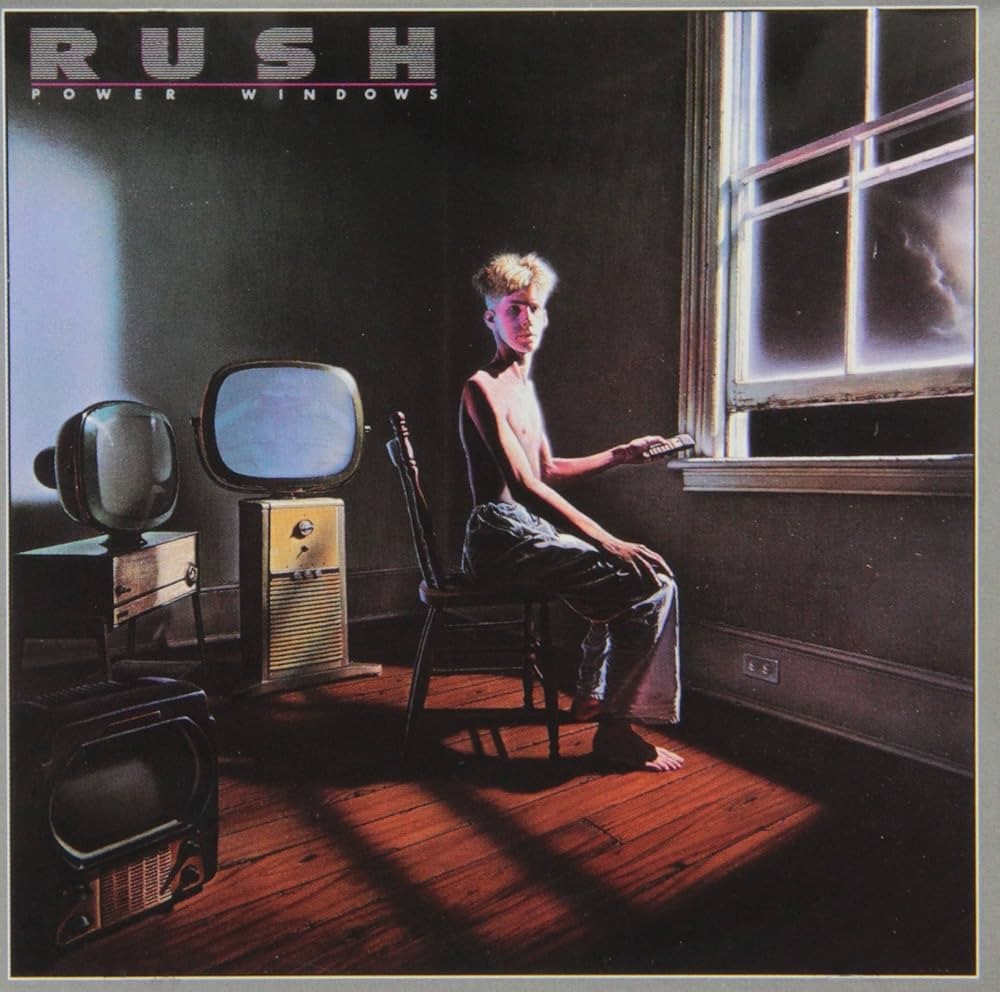 Cover for Rush’s Power Windows album. It is a sparse room with a young man sitting in a chair next to a partially open window. His head is turned to look at the viewer and he has a TV remote in his hand. Outside it is dark with a bolt of lightning. There are several older style TVs behind him at various angles.