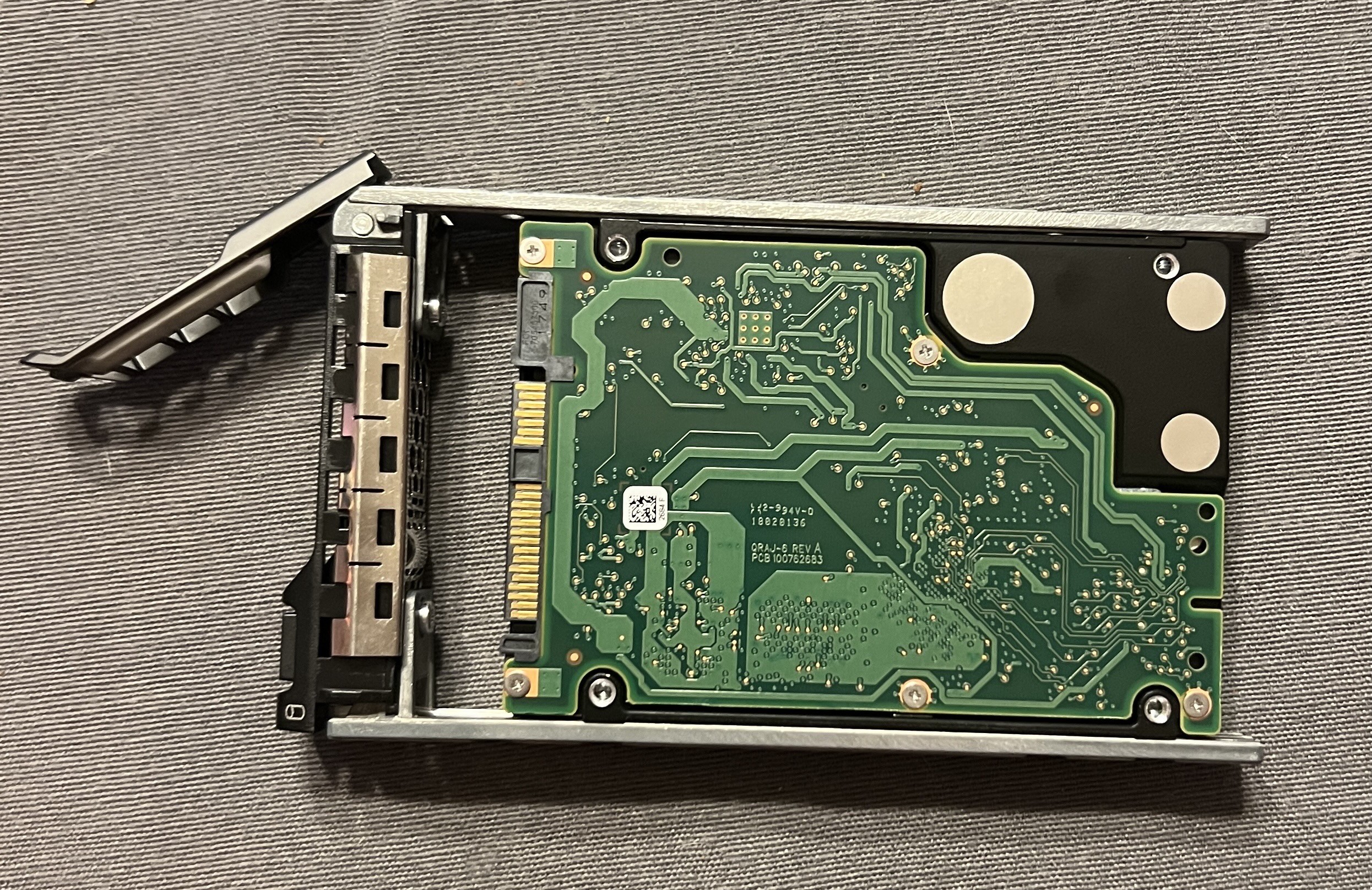 Photo of a 2.5 inch hard drive in a drive sled for sliding into servers. The drive’s gold contacts are clearly backwards so they won’t make contact when it slides into the server chassis. Some idiot named yours truly did that. 😜