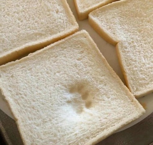 Photo of four sandwiches sitting on a plate, yet one mysteriously has a paw print shape that looks like a cat's paw. Of course, it couldn't be that because the kitties are not allowed on the counter...