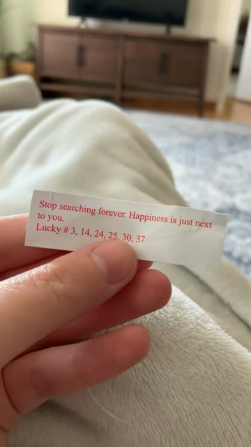 Someone looking at a fortune cookie paper with the following written on it:

Stop searching forever. Happiness is just next to you. 
Lucky # 3, 14, 24, 25, 30, 37

Thr video then pans over to a mostly orange cat (with a black spot on its side) who rolls over on its back while looking super cute. In the background another kitty can be seen munching on some kibble.