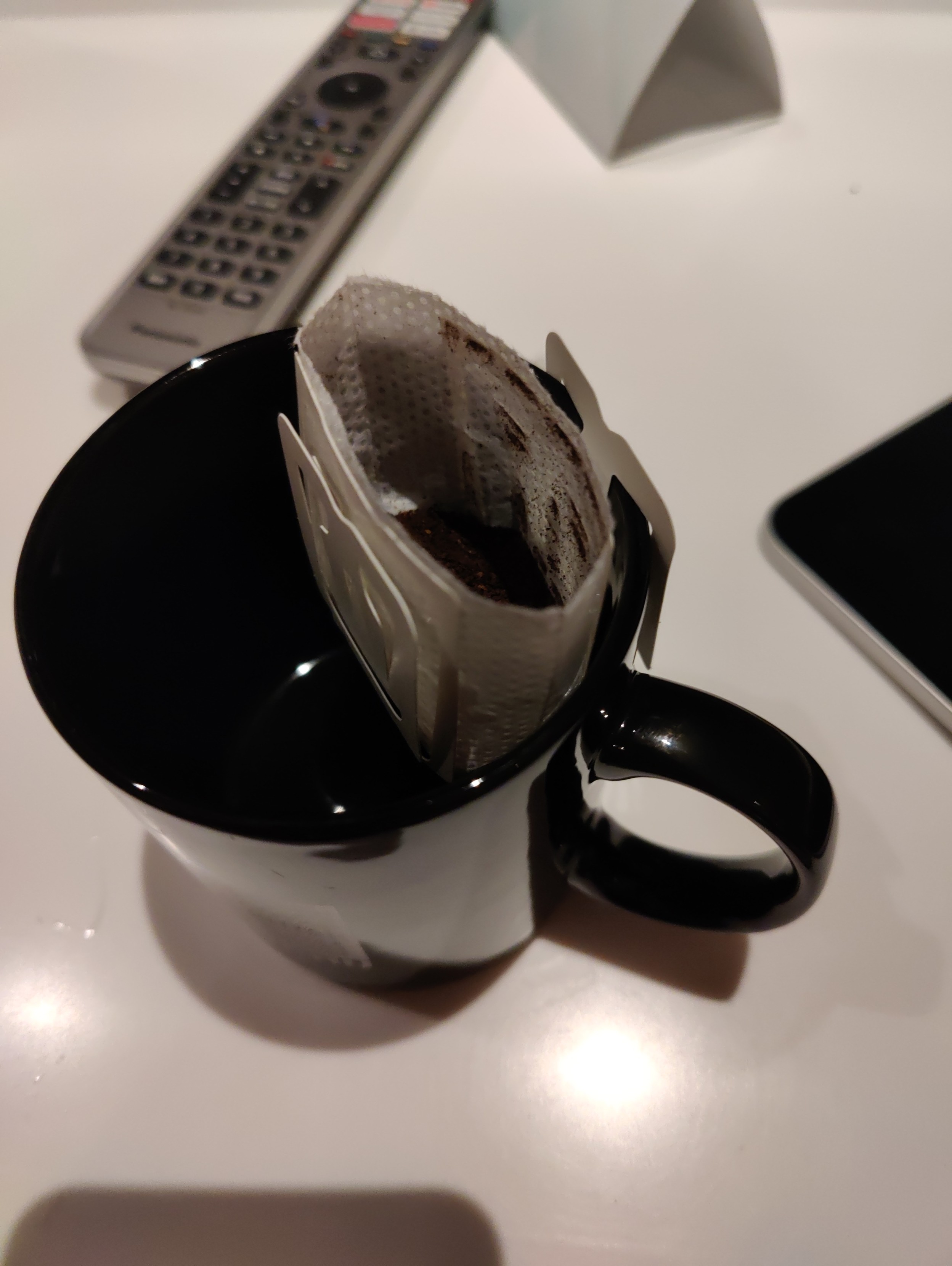 The bag torn open and attached to one side of the cup.  You can see coffee in it.  The other handle (for attaching the filter bag to the other side of the cup)  is not yet in use.