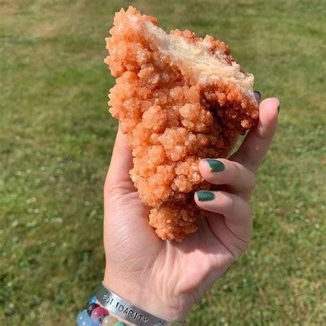 Photo of someone holding a rock (red calcite cluster) that looks like fried chicken. Mmm... looks tasty