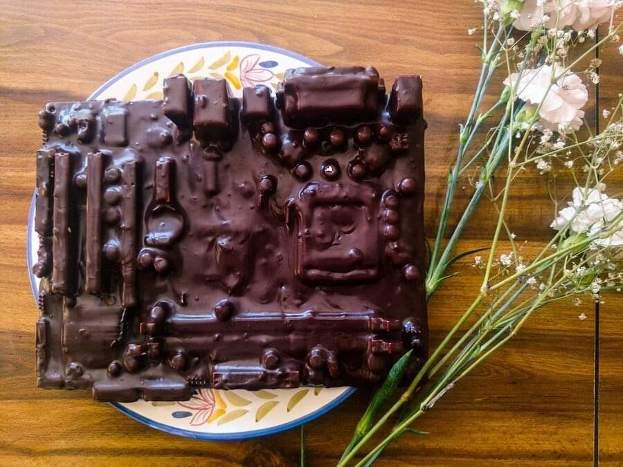 Chocolate coated motherboard on a plate next to some flowers.