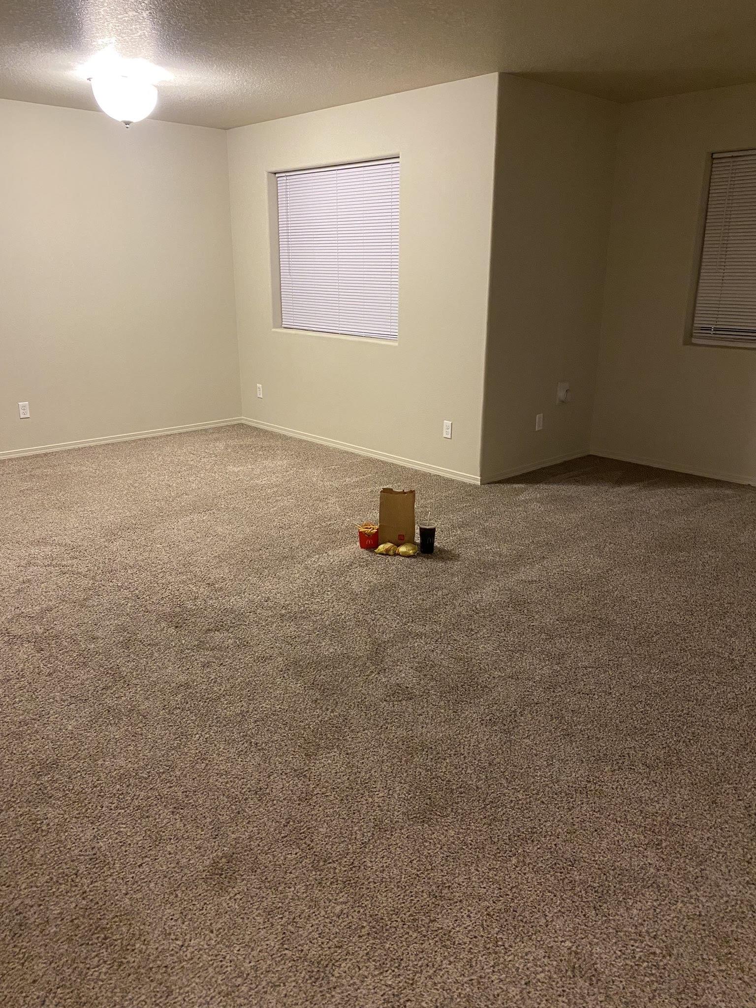 Photo of a bare apartment room with nothing in it except a paper bag with some McDonald's food sitting in the middle of the floor. Fries, a drink, and two wrapped sandwich bags can be seen around the baitโ I mean, tasty food.