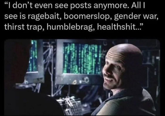 The image is a meme referencing a scene from the movie "The Matrix". It features a screenshot with text overlaid.

The scene appears to be set in a dimly lit, high-tech environment. Two figures are present. On the right, a man with a shaved head and a small mustache is visible. He is angled slightly towards the left of the frame, looking at the other person with a slight smile. The other person is mostly obscured, only their silhouette is visible on the left side, facing the man.

Behind the ma…