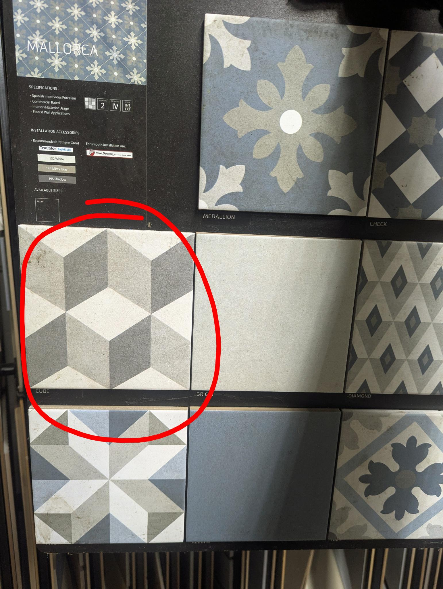 A tile sample board with 8 patterned tiles on them. One is patterned with 3D Cubes in the same style as the 1980's video game Q*Bert.