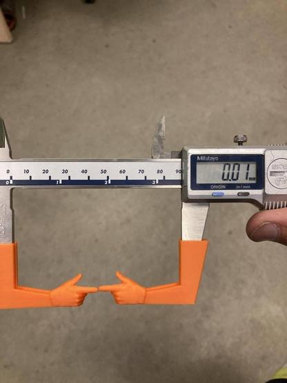 Photo of some Mitutoyo digital calipers with two orange 3d-printed arms sporting finger guns to pointing to the measurement area. The device is calibrated to the finger additions and displays a 0.01mm gap being measured.