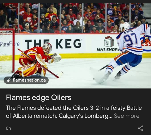 The image captures a dynamic moment from an ice hockey game. The scene is dominated by two main figures: a goalie in a red, yellow, and white uniform and a player in a blue, white, and orange uniform.

The goalie, wearing a mask and full protective gear, is in a defensive stance, leaning low to the ice near the goal net. His equipment, including pads and gloves, is designed to protect him from the puck. The goalie's stick is held in front of him, likely in an attempt to block an incoming shot. …
