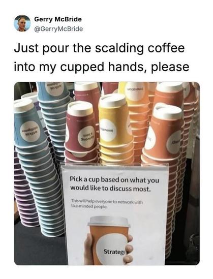 The image is a social media post, likely a meme or humorous observation. It features a photo of a display of paper coffee cups with various labels, accompanied by text.

The main focus of the image is the stacked coffee cups. They are arranged in multiple columns. Each cup has a different color and a label with a word or phrase, presumably related to topics for discussion. The labels include "Artificial intelligence," "Marketing & Sales," and "Innovation." There's a sign in front of the cups th…