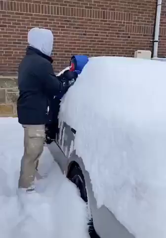 Video of a dad using his kid as a brush to squeegee the snow off the side of his car.