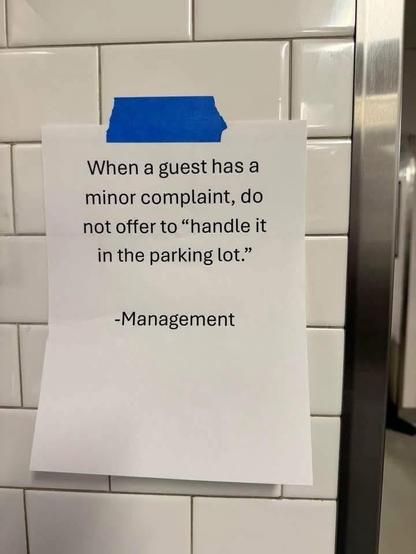 The image displays a white piece of paper with black text, taped to a tiled wall. The paper is oriented vertically and slightly angled, with its top left corner appearing to be the most securely attached. A strip of bright blue tape, with ragged edges indicative of it being torn, is affixed to the top of the paper, securing it to the wall.

The wall itself is covered in rectangular white tiles, arranged in a subway tile pattern. The grout lines are clearly visible, creating a grid-like texture.…