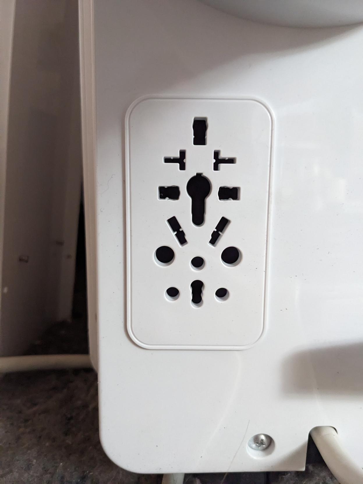 A power outlet with holes for well of 8 different type of power cord all bunched together. Pretty sure it's only meant for one type to be plugged in at a time, but it's impressive just how many regions it covers.