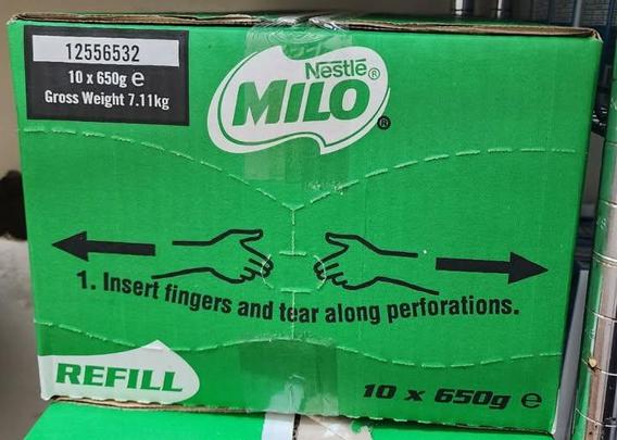 The image displays the front of a large, vibrant green cardboard box, which appears to be packaging for a product. The box is oriented slightly off-center to the left, with the top edge visible.

Prominently featured on the front is the Nestle Milo logo, a white oval with the word "MILO" in large, bold, green lettering. Above "MILO" in smaller white text is "Nestle" with a registered trademark symbol. To the left of the Milo logo, on a black rectangular label, is the product code "12556532" in …
