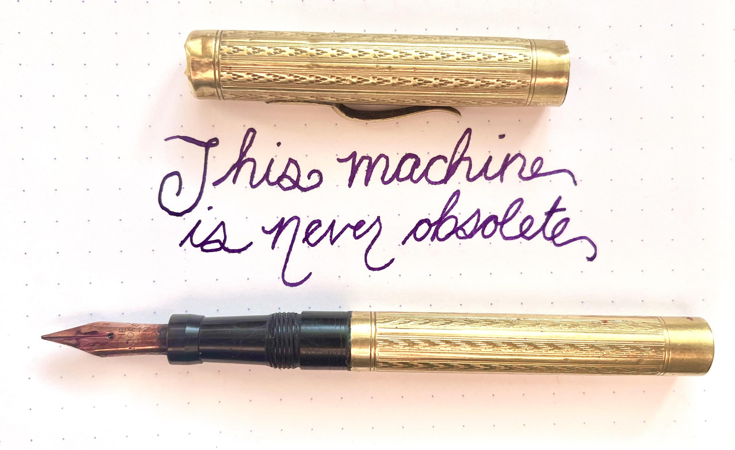 photo of a century-old gold plated fountain pen with sample cursive text: “this machine is never obsolete”