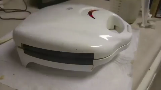 Video of someone filming their waffle maker in progress while it makes a funny squealing noise. After a bit, the squealing peaks and the waffle maker makes a fart sound as a bit of waffle batter pokes out some. The person filming it dies laughing the rest of the clip.