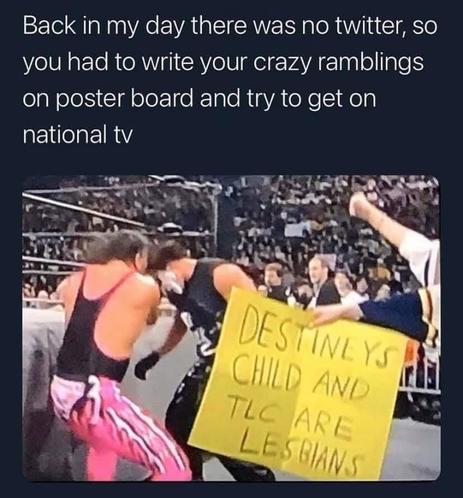 The image is a meme composed of text and a photograph. The text at the top reads, "Back in my day there was no twitter, so you had to write your crazy ramblings on poster board and try to get on national tv."

The photograph below shows a wrestling ring with two wrestlers in action. The wrestler on the left is wearing a black singlet with pink and black patterned wrestling tights. The wrestler on the right is wearing a black outfit with dark pants and appears to be in mid-action. In front of th…