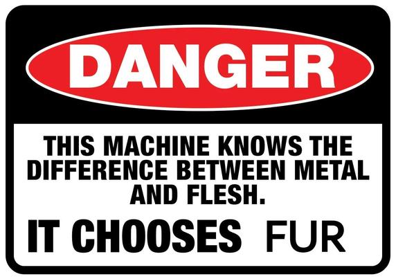 Warning sign that reads:

DANGER

THIS MACHINE KNOWS THE 
DIFFERENCE BETWEEN METAL 
AND FLESH.

IT CHOOSES FUR