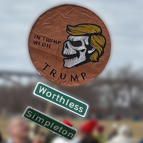 A gold coin with Trump’s face on it and signs saying “worthless” and “simpleton” underneath