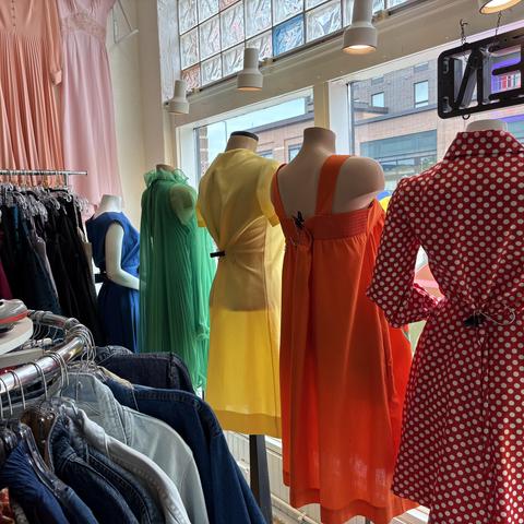 a window display with a rainbow of dresses