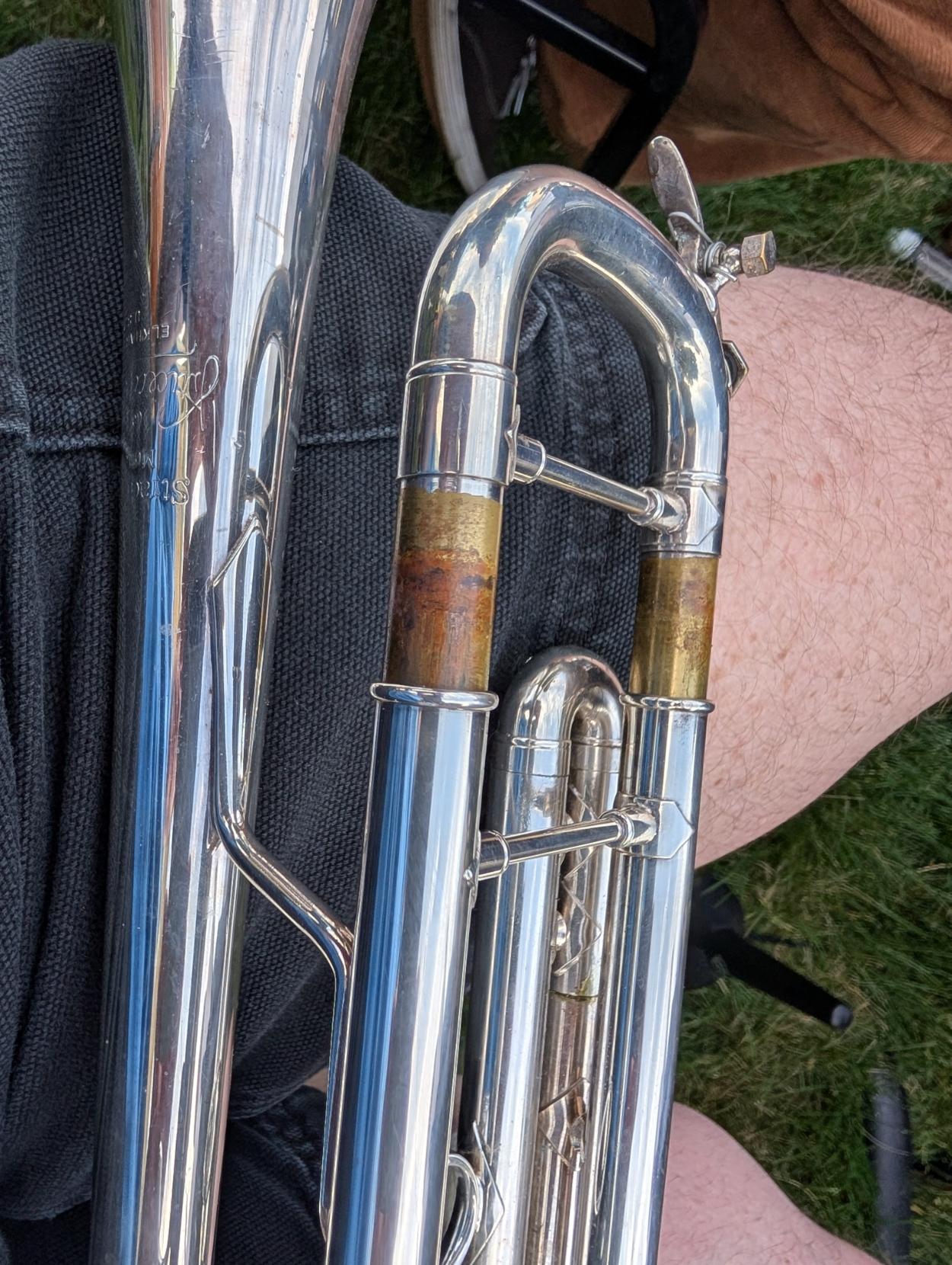 A silver trumpet with the tuning slide out close to 3 centimeters.