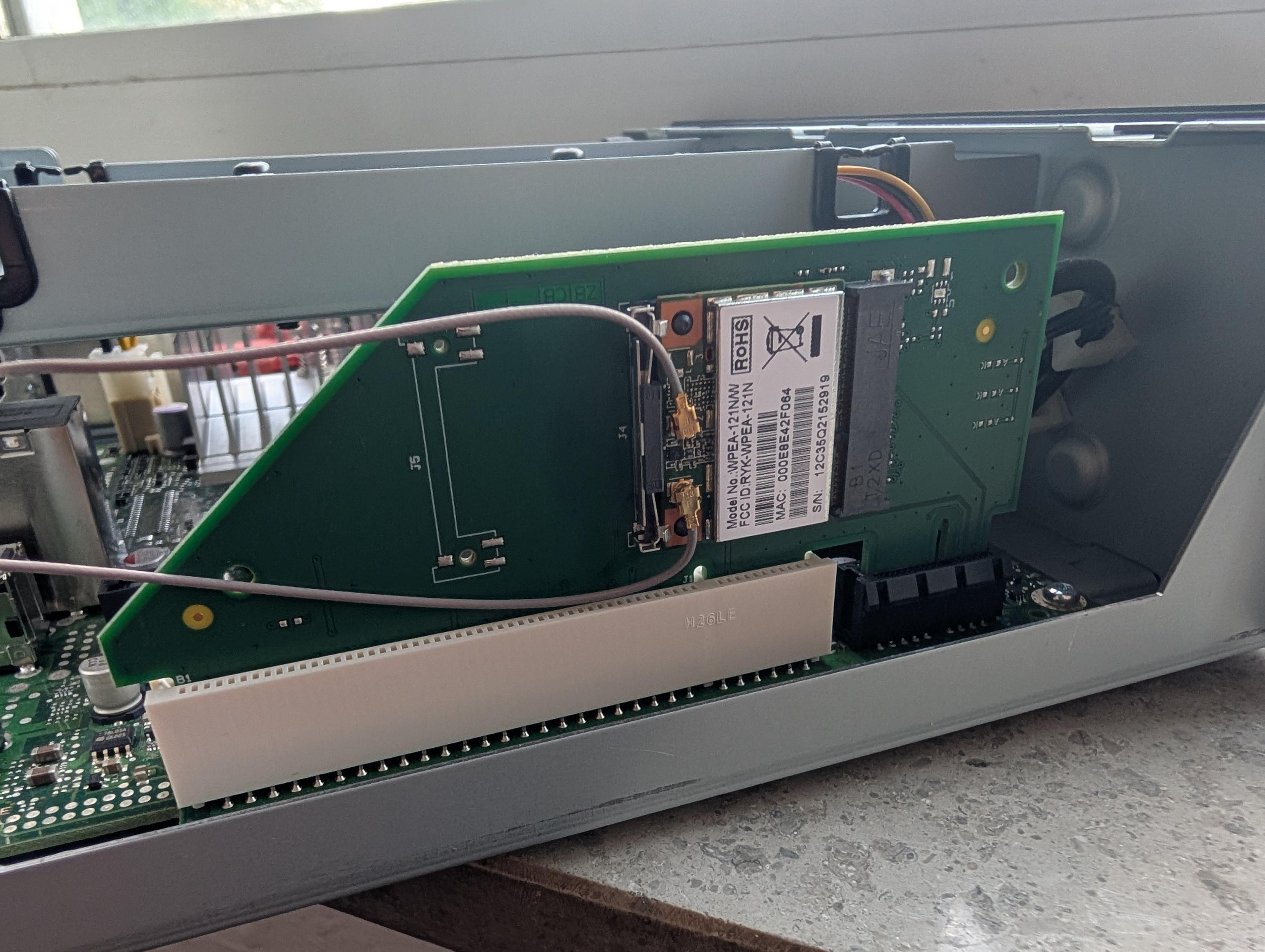 A riser card on a mainboard that is connected to a PCI and PCI-Express slot at the same time. On the riser card a wireless network card is installed.