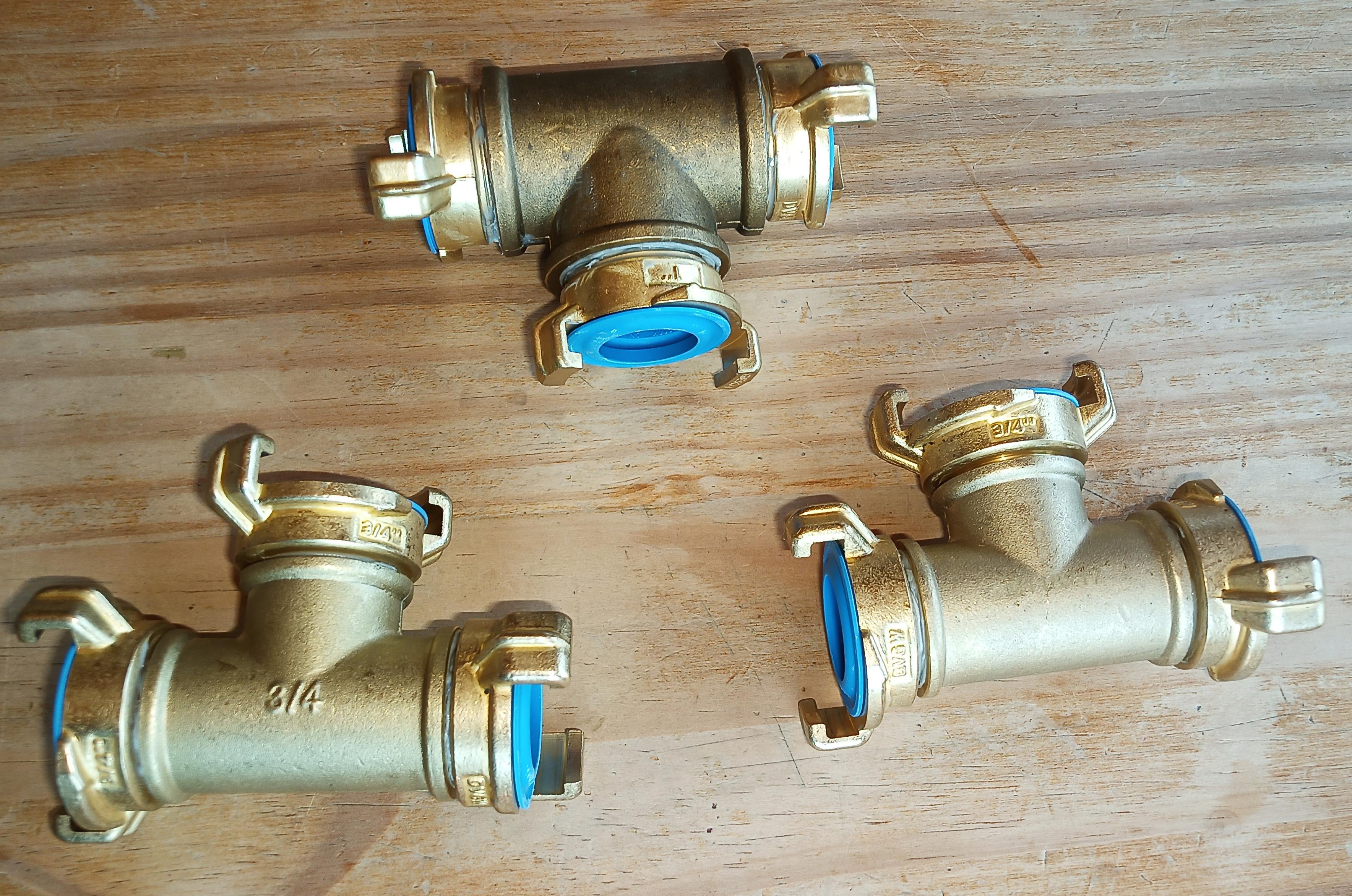Drei Wasserrohr-T-Stücke aus Messing, jeweils mit drei Klauenkupplungen Typ Geka. Man sieht an den leuchtend blauen Dichtungen, dass es sich um Original-Geka mit Trinkwasserzulassung handelt.