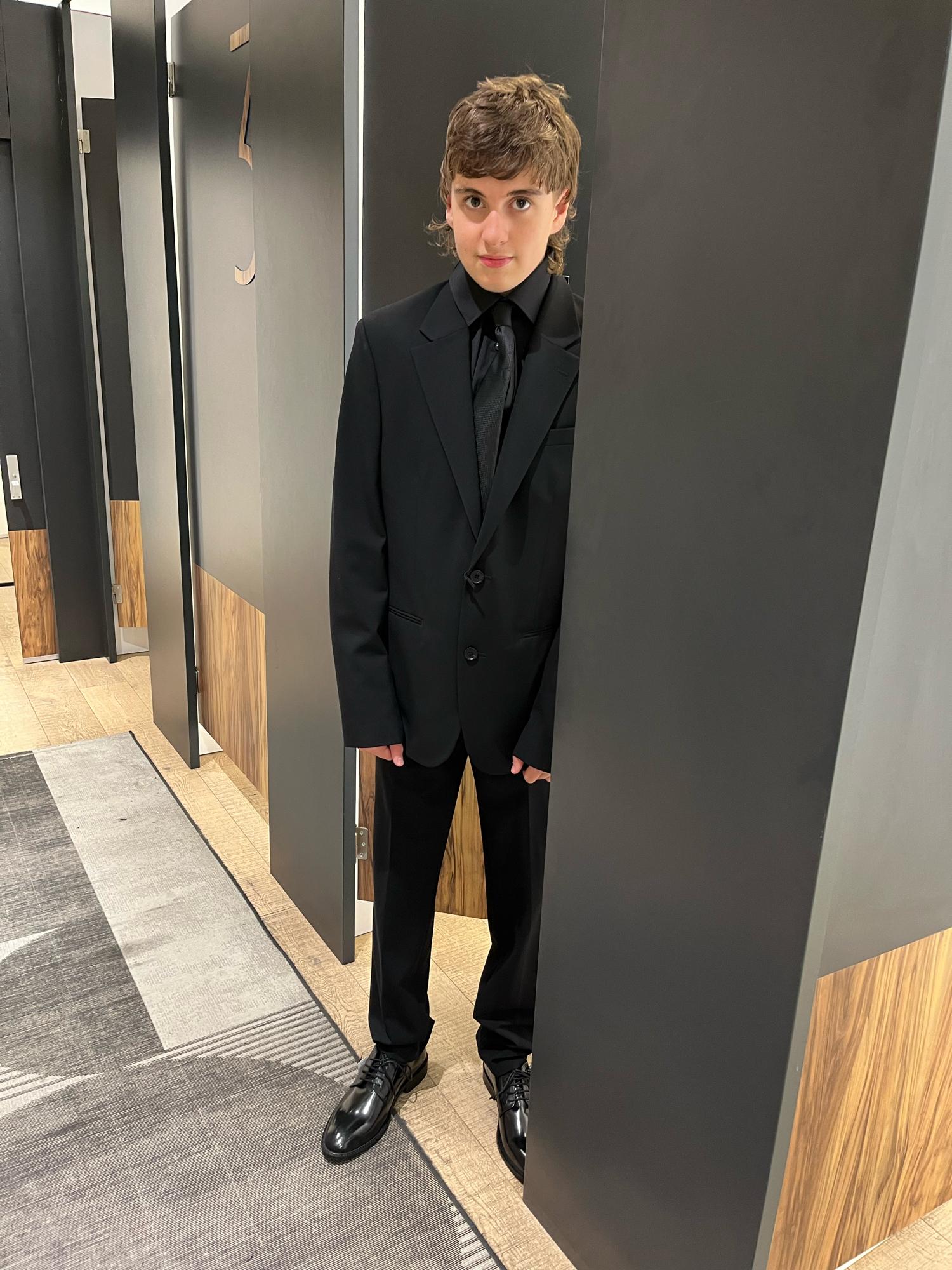 KP in a black suit, black shirt, black tie