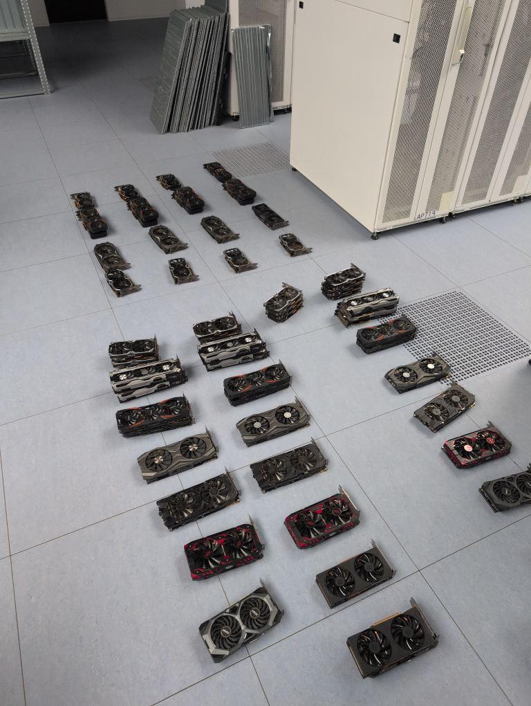 Photo of a couple dozen GPUs spread out across the floor.