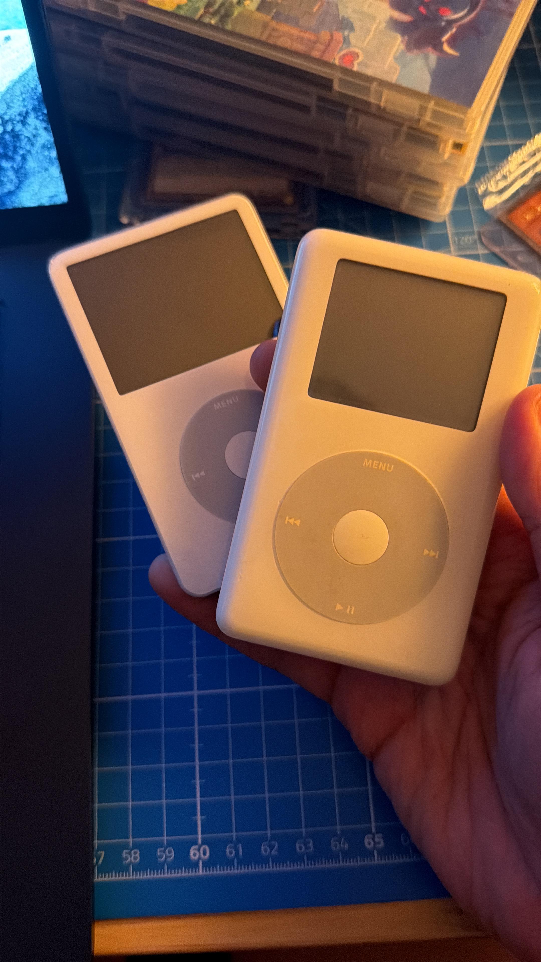 Two white iPods in front of a blue deskmat