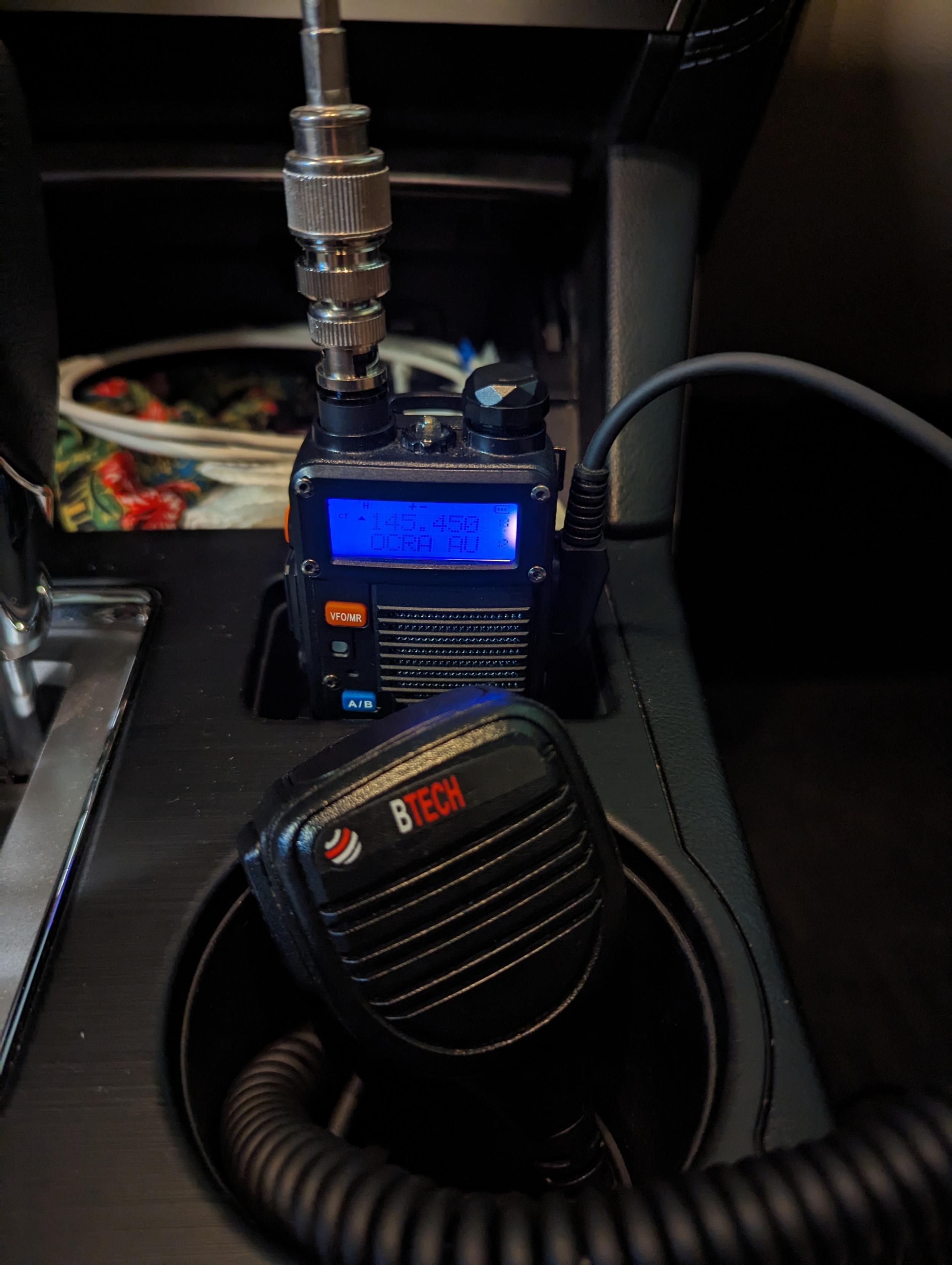 Baofeng F8HP HT in the center console of a Subaru Outback. The HT is connected to an RG-8 coax using a couple of adapters. There's a BTech brand hand mic in the foreground that's connected to the HT.

(The frequency in the HT is for my local club repeater when I was testing the setup, not the repeater I connected to in Indiana.)