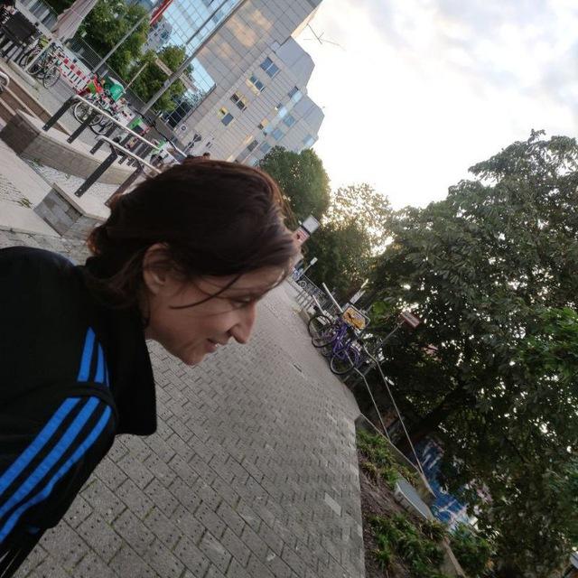 Links unten in der Ecke Julia Seeliger, dahinter Hochhäuser, gepflasterte Strasse, rechts Bäume (Berlin Schillingstrasse Häuserschluchten)