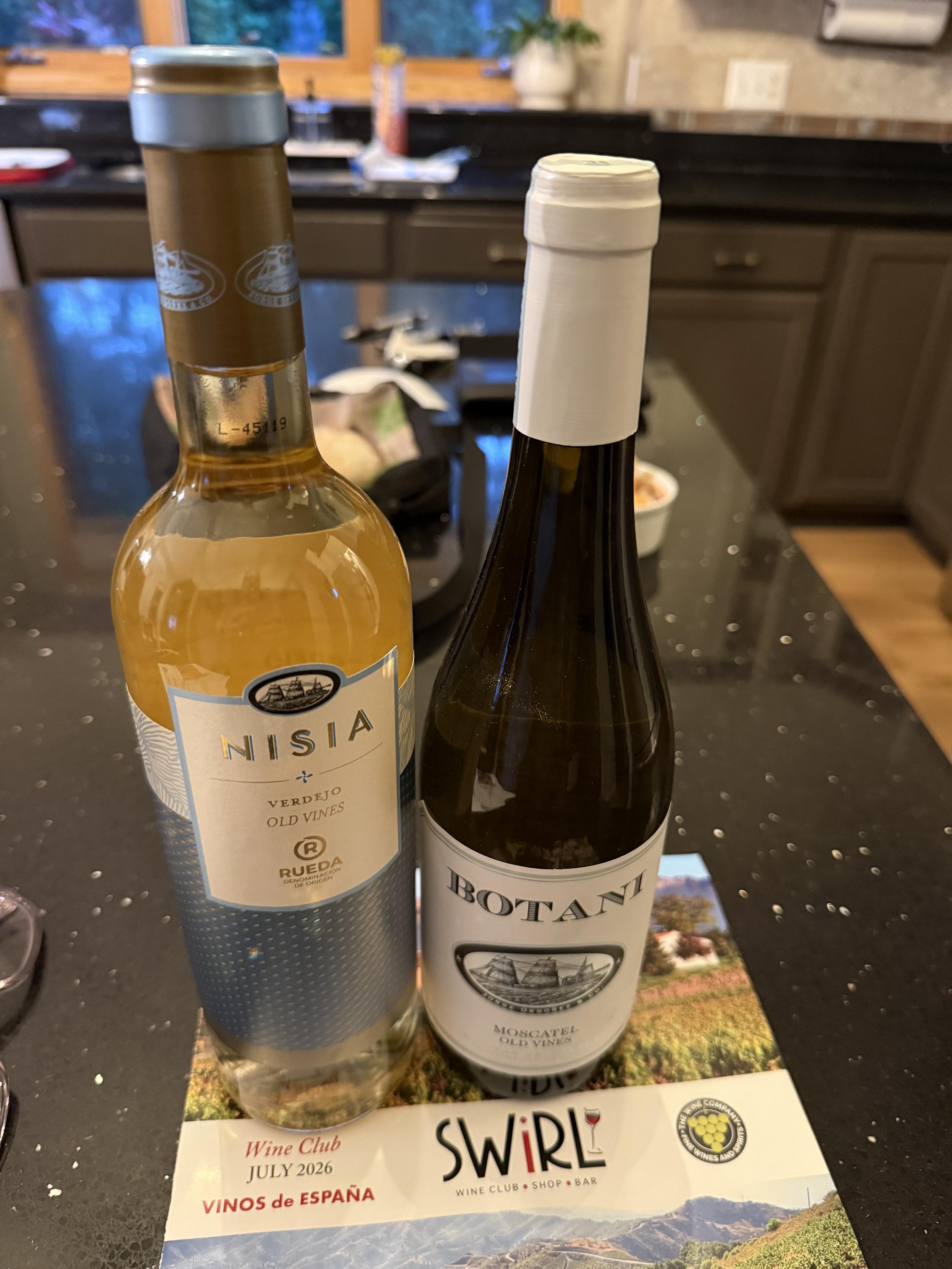 Two bottles of Spanish wine, one golden yellow and the other dark green.