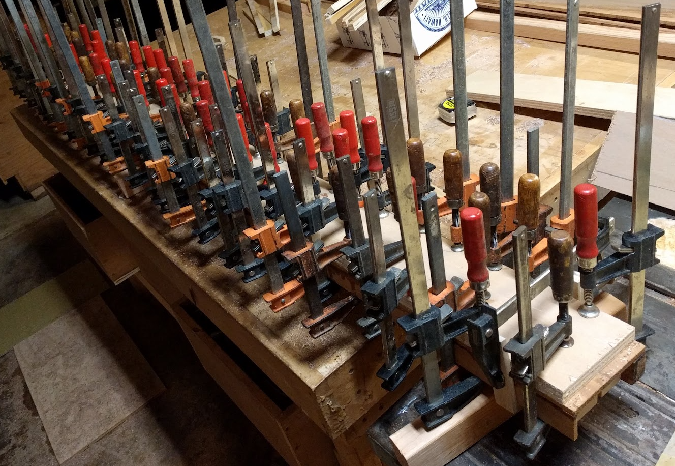 Woodworker's shop gluing a long board with *lots* of clamps