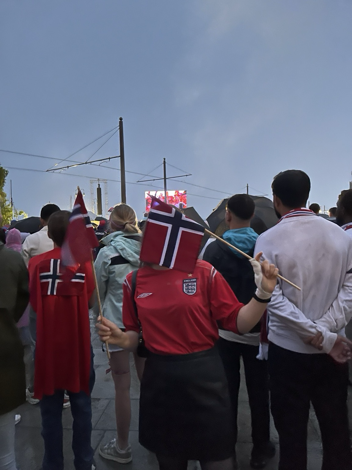 A picture of a girl in England sports T-shirt holding two Norwegian flags during 2026 Word Cup quarterfinal football match between Norway and England teams.