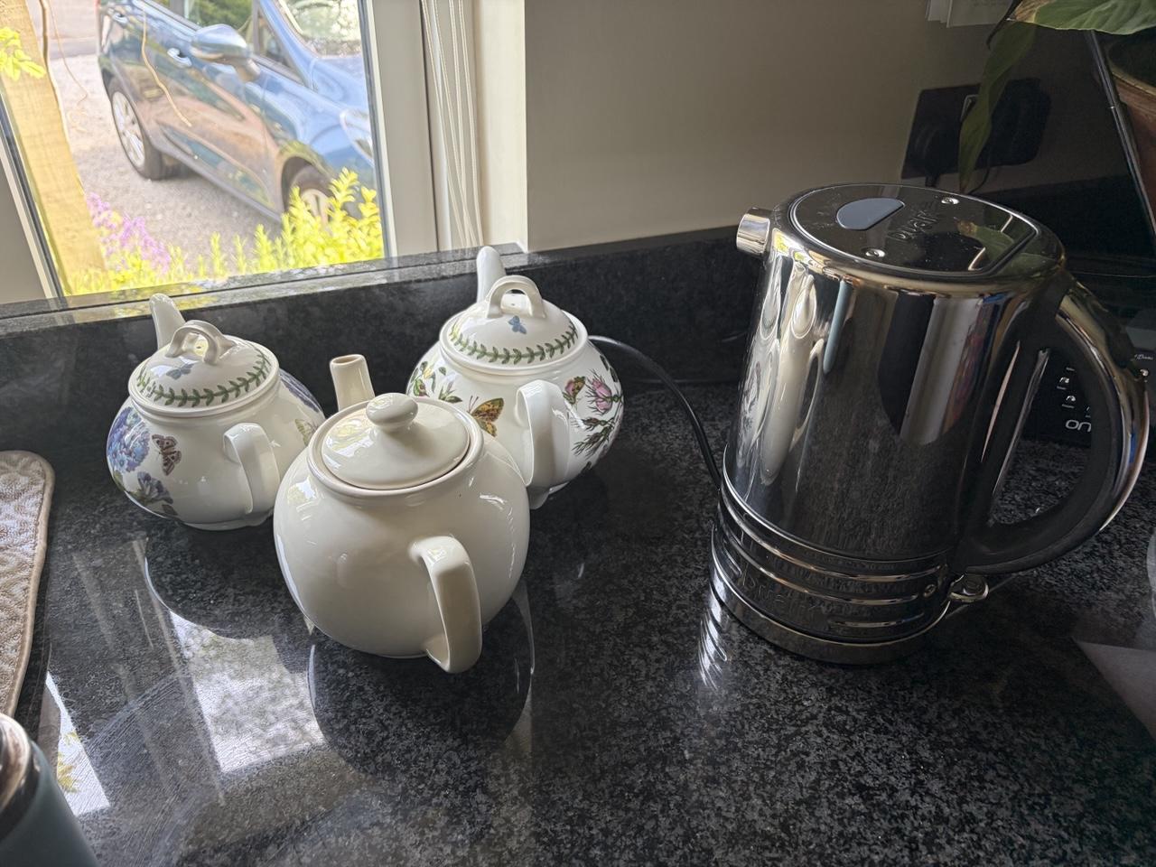 Three white tea pots lined up by a shiny metal kettle ready to used by the tea drinking masses of the Gent family (and hangers on)