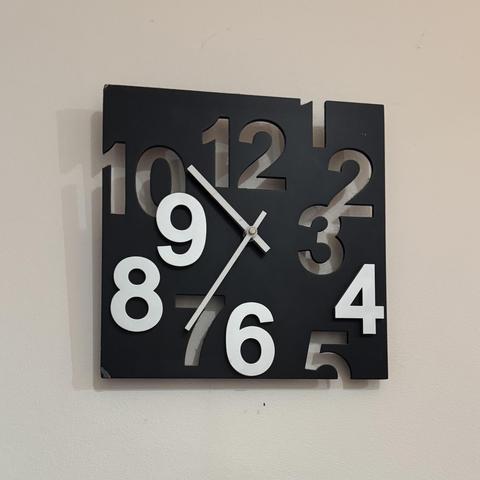 Photo of a square, black clock with all the numbers offset different distances from the middle. The 1, 2, 3, 5, 7, 10, and 12 are cutouts, while the 4, 6, 8, and 9 are solid white. Oh, and 11 is completely missing for some reason.