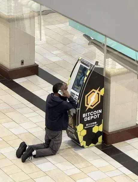 A picture of someone on their knees in front of a Bitcoin Depot ATM, on their phone, seeming to be in despair
