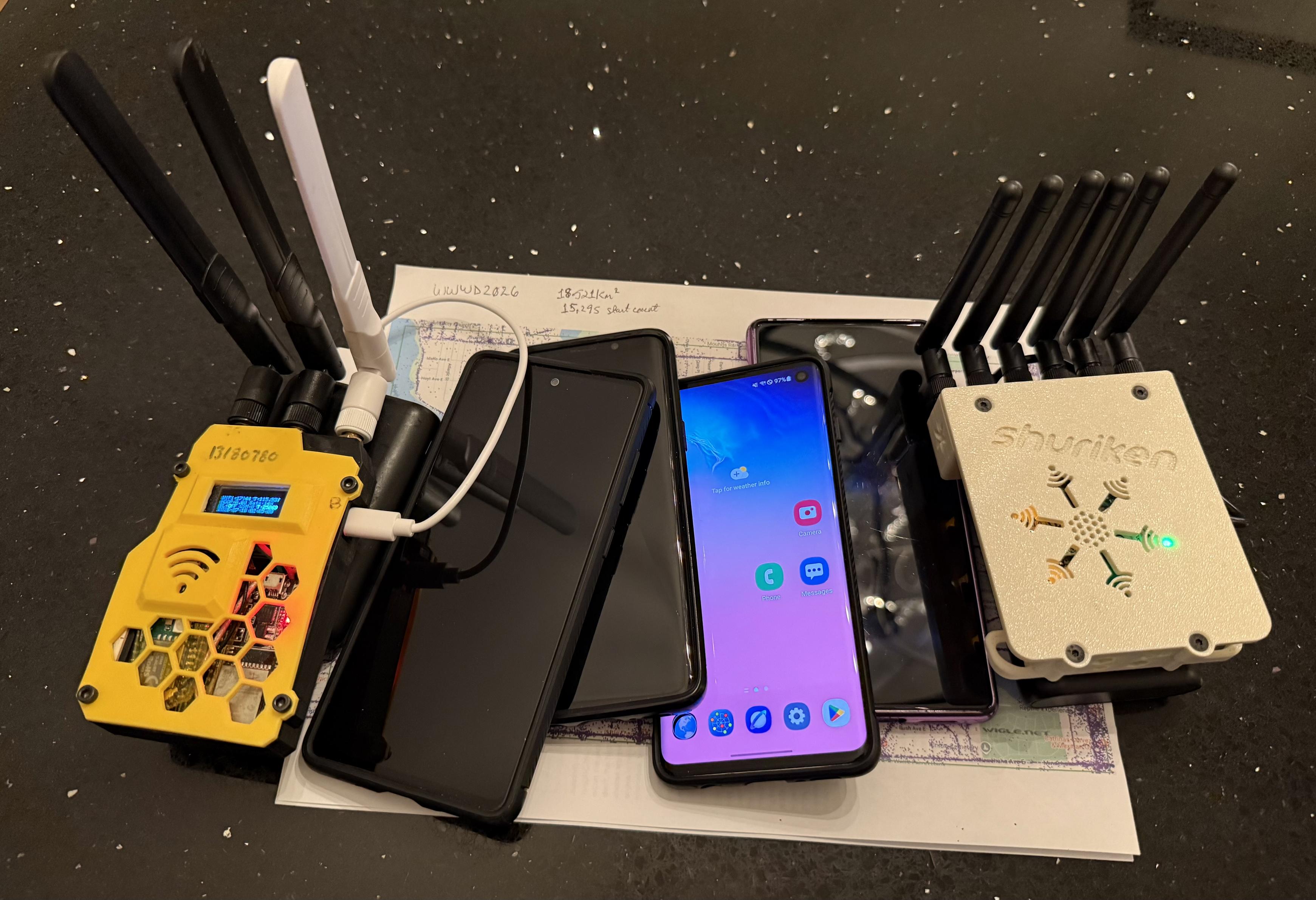 A photo taken of wardriving gear - left to right - JHewitt 5G, Galaxy S20, S10,S9, Pixel 6, and a WiFi Shuriken
Underneath is a paper map