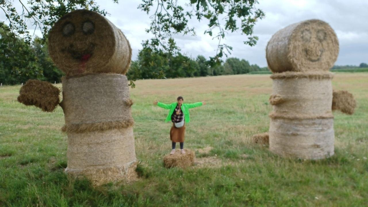 Ein Mensch zwischen zwei riesigen lachenden Rundballen-Figuren