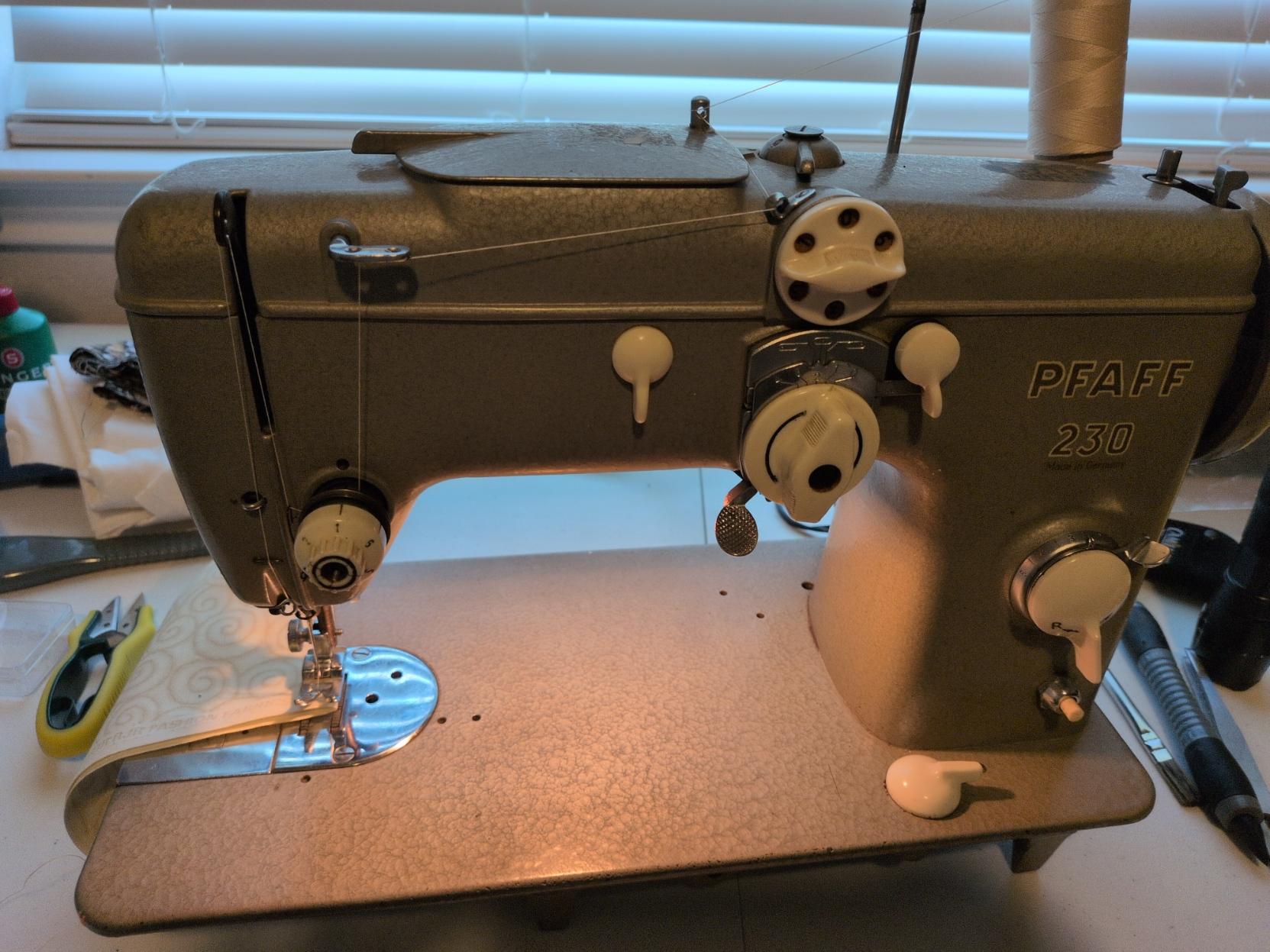 Pfaff 230 with the lamp on and some test thread and fabric loaded up. It weighs about 20kg and is a mechanical marvel. The only electrics are a motor, pedal controller and lamp.