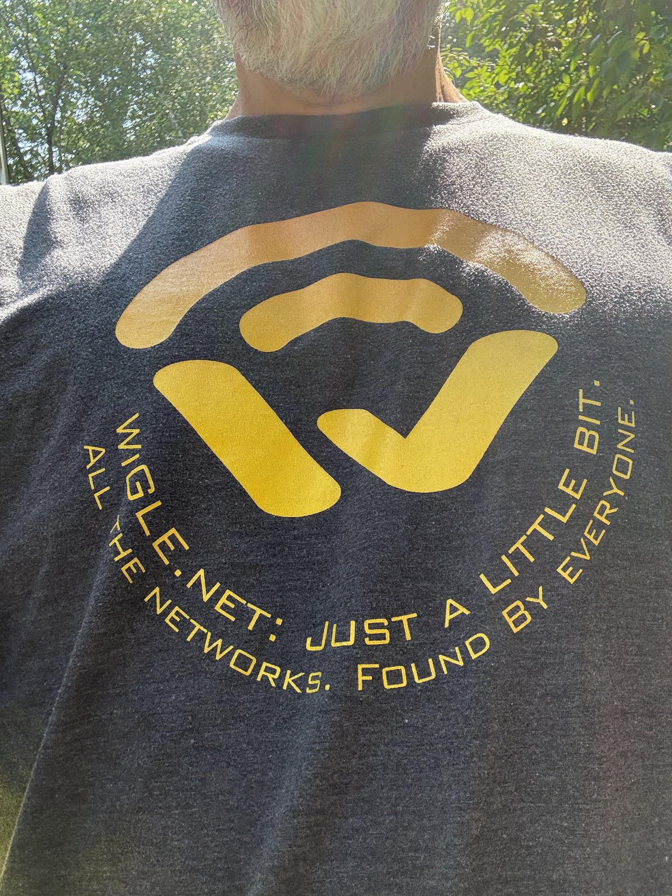 A gray t-shirt shows the Wigle logo and says

Wigle.net: just a little bit.
All the networks. Found by everyone.