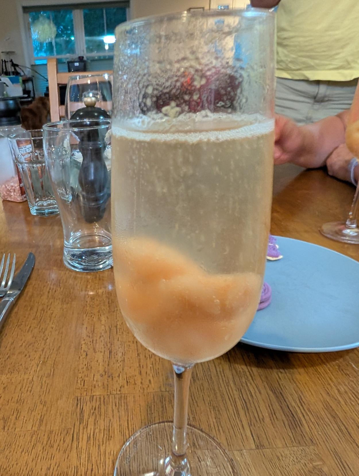 A champagne flute with champagne and a small lump of sorbet in the bottom