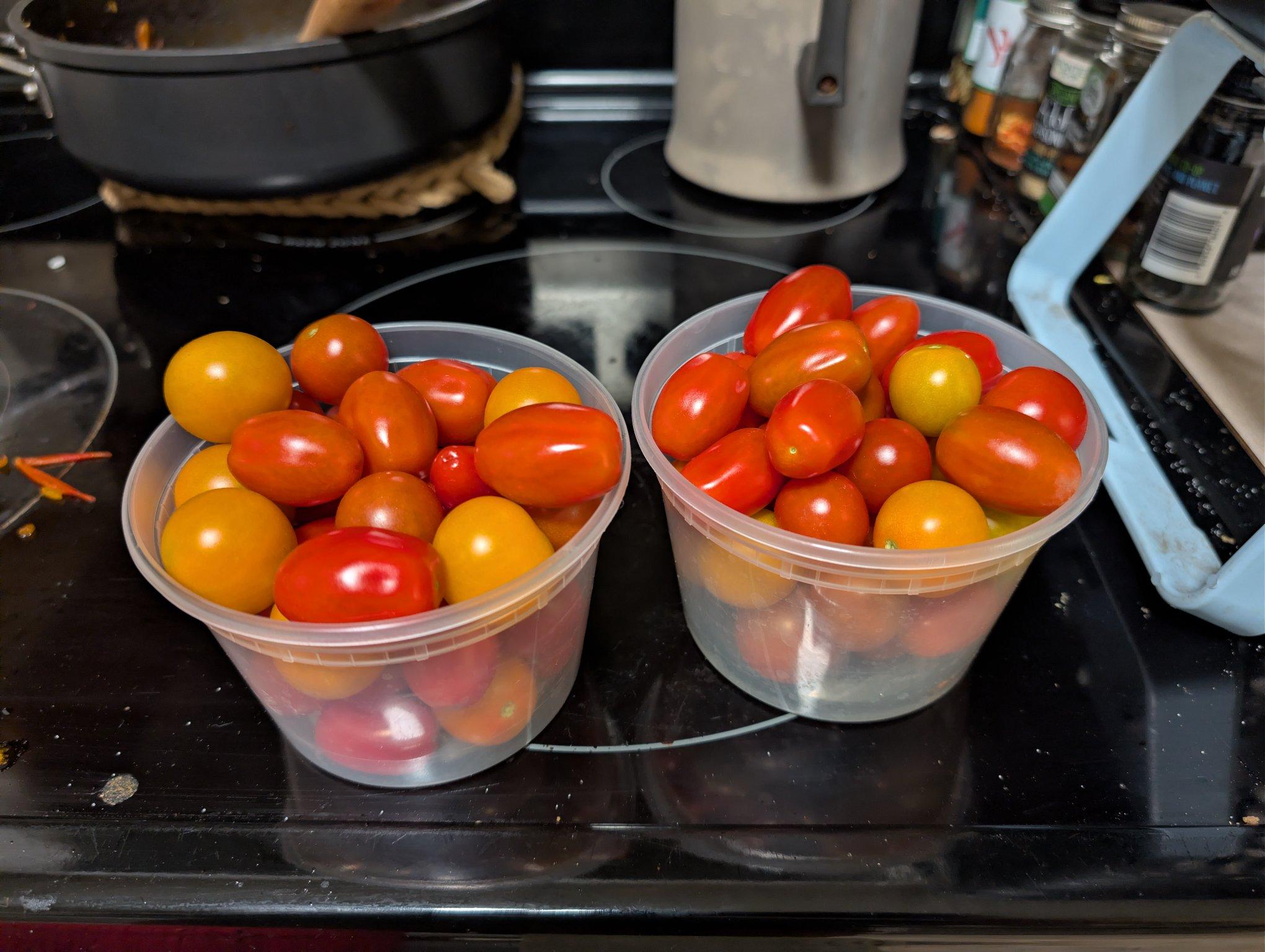 Two plastic takeout pints of sunset colored cherry tomatoes with a few red grape tomatoes sprinkled in