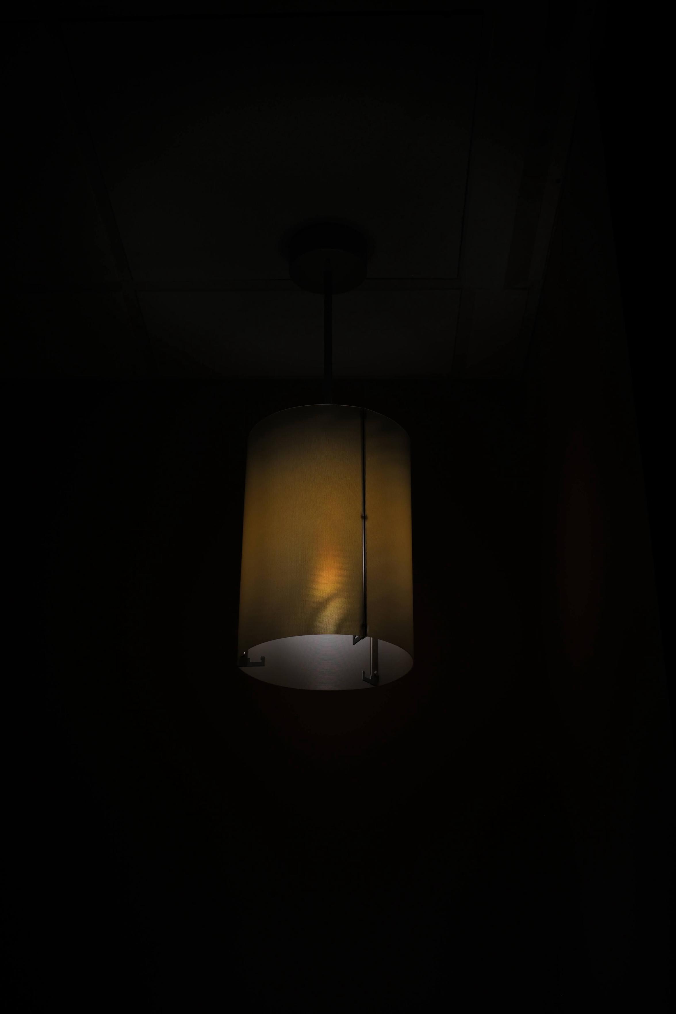 A dim ceiling lamp in a very dark room