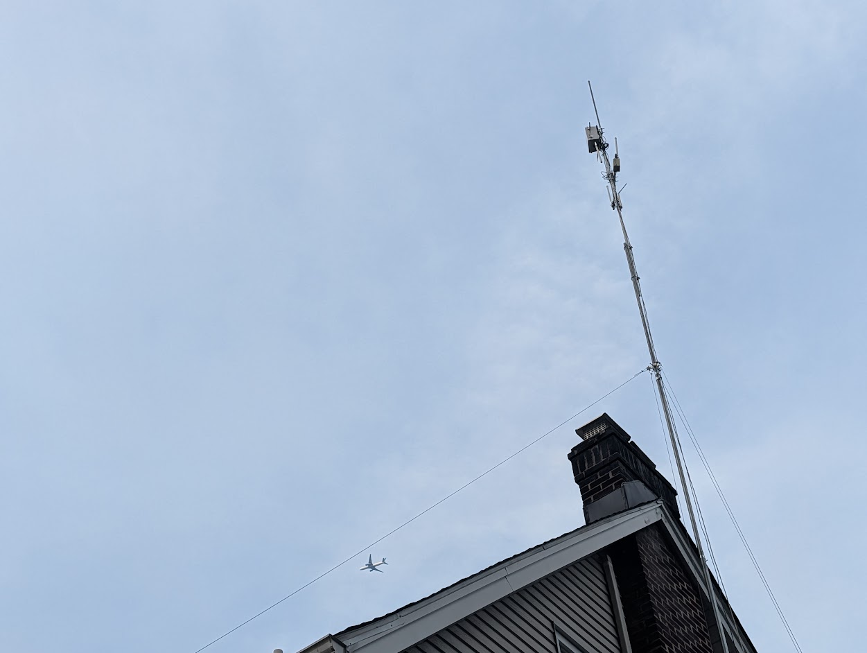 pic of a bunch of antennas on a mast about 15 feet above a roof.